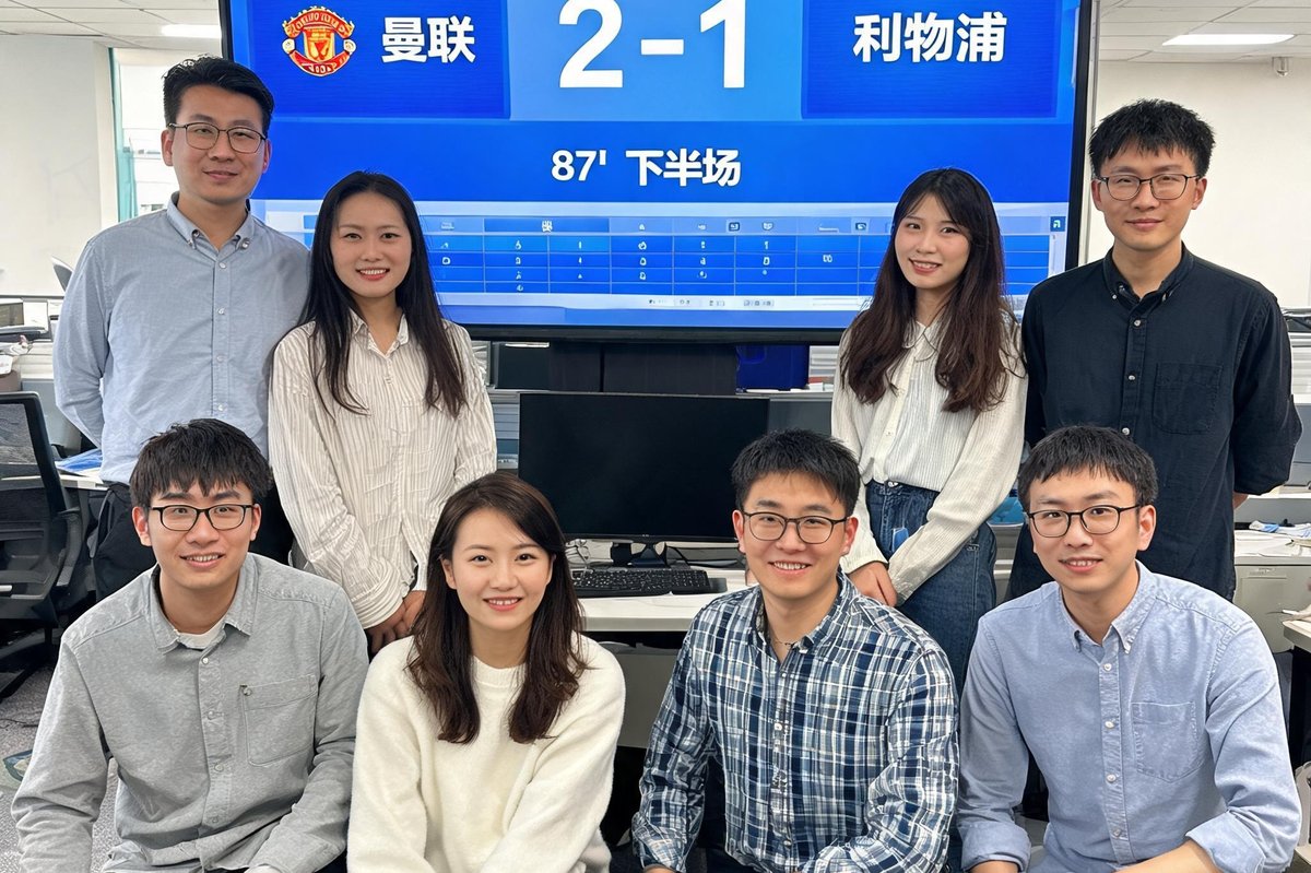 球探足球即时比分旧版本八人团队在办公室的合影，背景是显示器上的实时比分界面